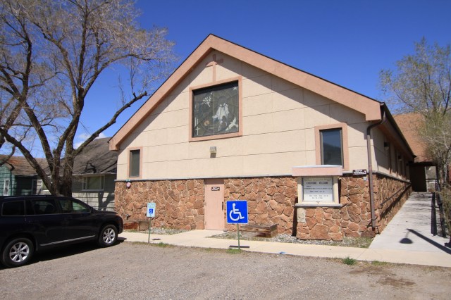 A tan church building is shown, with two accessible parking spaces in front of the church. A blue SUV is shown to the left of the parking spaces.